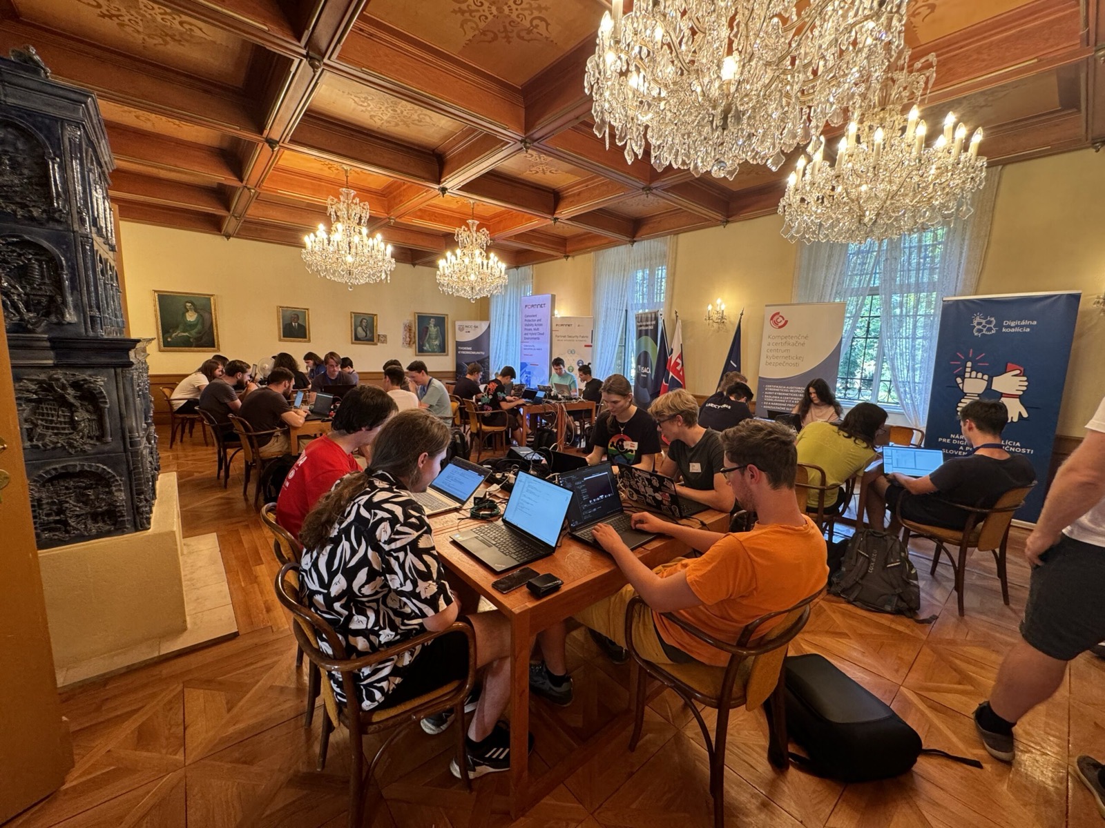 Sústredenie v historickej sále s lustrami, hráči riešia CTF úlohy